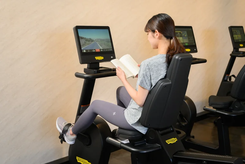 TSUTAYA Conditioning 福井高柳店のバイクマシンで本を読みながらトレーニングをする様子