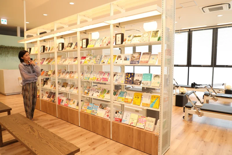 TSUTAYA Conditioning PILATES 宇都宮駅東口店のブックラウンジで本を選ぶ様子