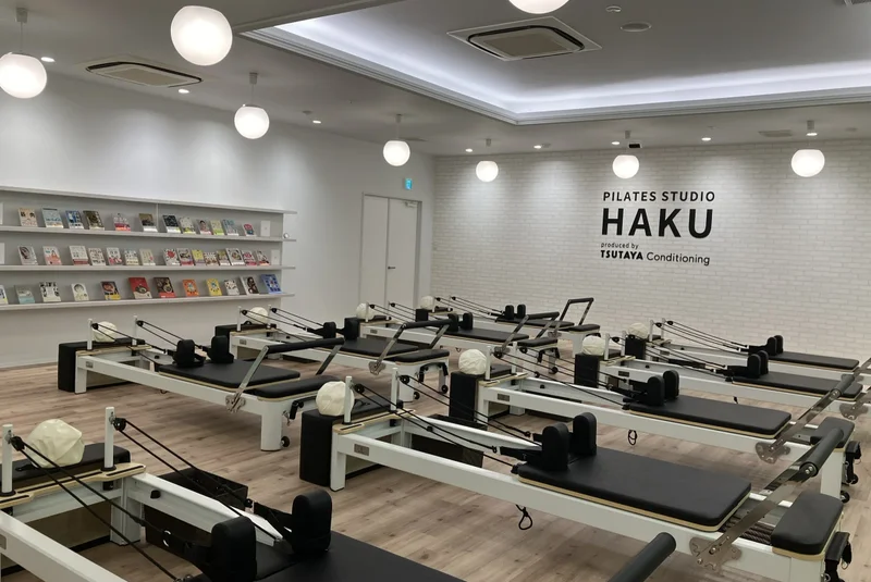 PILATES STUDIO HAKU 西条店の本棚とロゴ壁を望むスタジオ全景